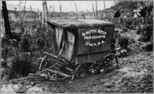 Covered carriage advertising Smith Bros of Owaka, in mud on the main road to Houipapa