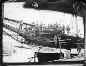 Prow of the sailing ship Hurunui showing the figurehead, and members of the crew posing for the camera, photographed at Port Chalmers