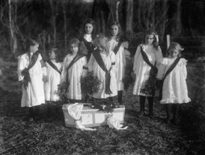 Young girls standing around a baby's coffin