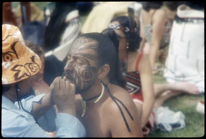 Woman applying moko to Maori performer