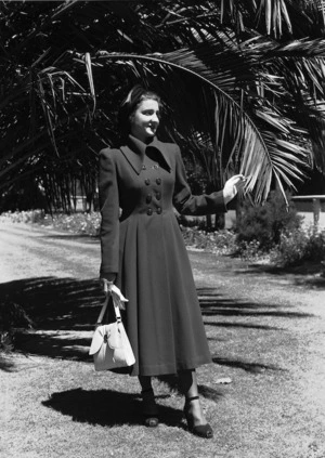 Model in a coat, hat and shoes, with gloves and a handbag