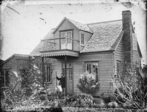 House in Wanganui, with man holding a Maori paddle