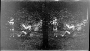 Two unidentified young children in bathing suits, playing with a water hose, location unknown