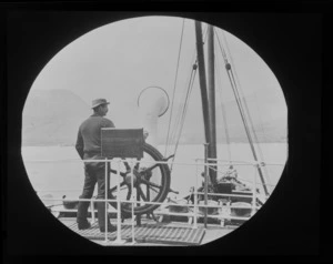 Unidentified man at the helm of a passenger steam boat, [Queenstown-Lakes District]