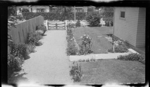 View down a shingle driveway by a wooden house to a street of unknown location, [Dunedin City?]