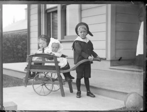 Three unidentified children, outside a house, location unidentified