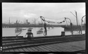 View of cargo ships, fishing boat and a long wooden wharf, [Oamaru?] Harbour, South Canterbury Region