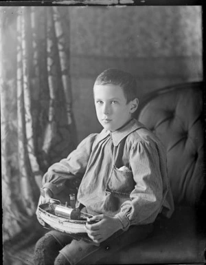 Owen William Williams, with a model ship of the 'Apollo', probably in his home, Royal Terrace, Kew, Dunedin