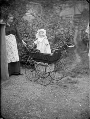 Baby Edgar Richard Williams, standing in a pram, including Lydia Williams nearby, location unidentified