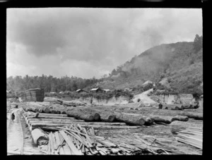 Timber mill, Kakahi, Manawatu-Whanganui, including houses, road and a small child walking along a path near logs