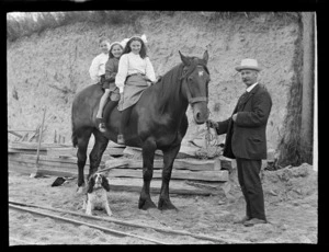 Two unidentified girls and a boy, on a horse, including a dog and an unidentified mature man holding the reins, Kakahi, Manawatu-Whanganui