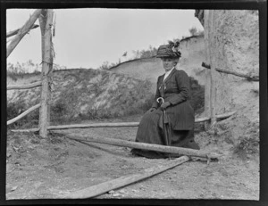 Lydia Williams sitting on a Manuka fence pole beside a bank, Kakahi District, Manawatu-Whanganui Region