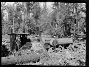Tree felling, William Williams and unidentified men beside a steam train and carriage with a newly chained log deep within an unknown forest, Kakahi District, Manawatu-Whanganui Region