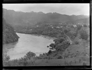 Settlement of Pipiriki beside the Whanganui River, with Pipiriki House and other buildings and forest covered hills beyond