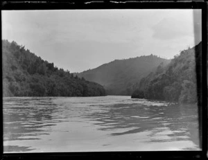 View off a boat on the Whanganui River with forest covered river banks and hills beyond