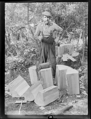 Wooden roofing shingles, with unidentified man using a mallet and axe to split blocks of wood in the process of making shingles, with bush behind at an unknown location