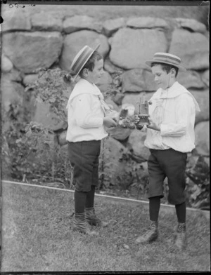 Owen Williams, left, and Edgar Williams, who is holding an unidentified metal object, in a garden, Dunedin
