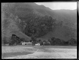 Family on the beach with house and boat shed behind, Marlborough Sounds