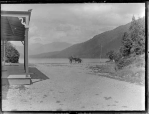 Passengers in Model T Ford car near waters edge, with verandah of house visible on left, Marlborough/Nelson District