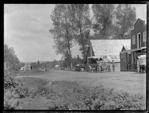 Small settlement with passengers in Model T Ford car, possibly part of group Lydia and William Williams are travelling with, and unidentified children in front of house, West Coast region