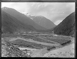 Small settlement with railway bridge over river valley between mountains, possibly Arthurs Pass, West Coast region
