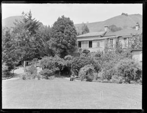 Lydia Williams sitting in front of garden and homestead with croquet hoops in lawn in foreground, Marlborough/Nelson District