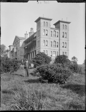 Elderly man with rake in the garden below the main building of Auckland Public Hospital