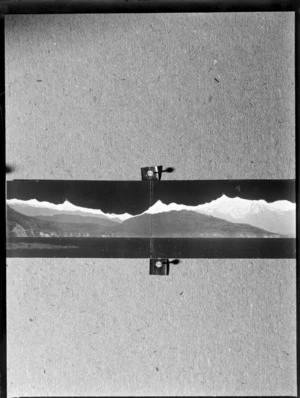 Panoramic photograph of mountains and sea, pinned to a wall, location unknown