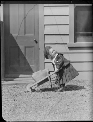 Portrait of a young Edgar Williams with a toy wooden wheelbarrow in front of the family house, 'View Bank', Maitland Street, Dunedin, Otago Region