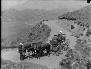 Two unidentified men with a two horse wagon on an unknown mountainside dirt road above an unknown valley, Queenstown District, Central Otago Region
