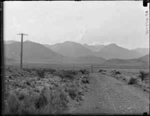 Two bicycles on the West Coast Road to Arthur's Pass with a tussock covered landscape and unidentified mountains beyond, Canterbury Region