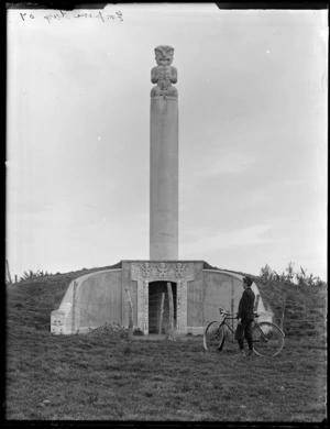 The Kaiapohia Memorial or 'Tiki" to the Ngai Tahu people with [Owen Williams?] and bicycle, Rangiora District, Canterbury Region