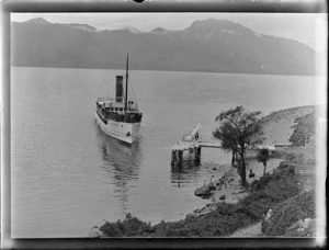 The steam ship [TSS Earnslaw?] on Lake Wakatipu approaching [Walter Peak Station?] jetty with unknown mountains beyond, Queenstown District, Central Otago Region