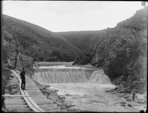 A young man, probably Owen Williams, standing next to Waipori River dam, Clutha District, Otago Region