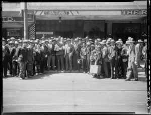 Wrestler Mr Billy Meeske with a crowd of men in front of tobacconist shop
