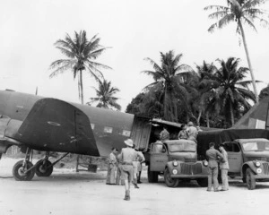 Military trucks alongside a Dakota DC-3 aircraft, Espiritu Santo, Vanuatu , during World War II