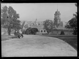 Lydia Williams and unidentified man seated on a park bench in Albert Park,with Auckland Art Gallery in background