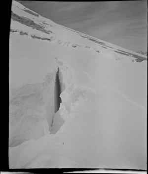 Part one of a stereograph showing view into crevasse, with snow tracks of mountaineers beside mountain slope, [Aoraki/Mt Cook National Park]