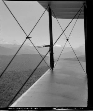 Part two of a stereograph showing view of bi-plane wing, with glacier and mountain peaks beyond, West Coast Region