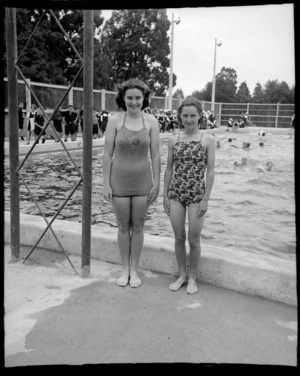 Two unidentified girls in togs with school children behind at a public swimming pool