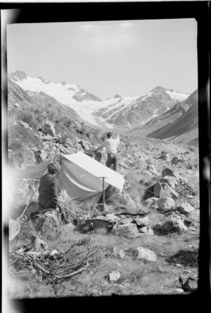 An unidentified man and a woman making camp high in the Forbes River Valley looking to Mount D'Archiac, the South Forbes Glacier and The Onlooker peak, Inland Canterbury Region