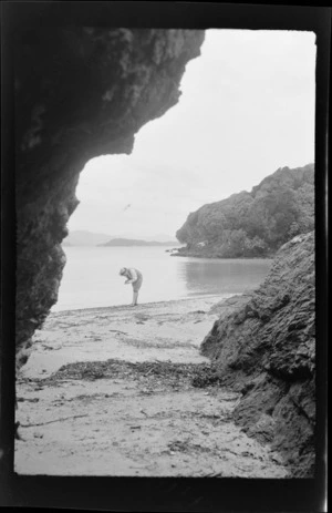 Alice Williams looking at items on a beach by the shore line, Stewart Island, (Rakiura)