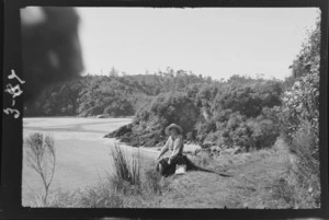 Alice Williams sitting on a path by beach and bush area, Stewart Island, (Rakiura)