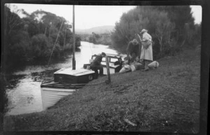 William Williams, Alice Williams and unidentified men unloading luggage from a launch on unknown river, Stewart Island (Rakiura)