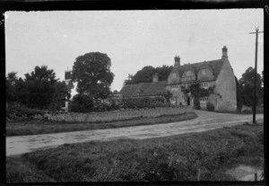 Lydia Williams and a man in front of the three storey Plough Inn building and cottage with garden within the town of Pau, South-west France