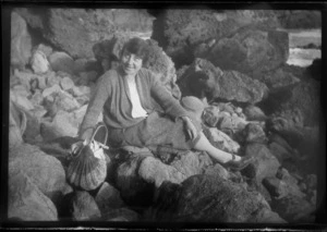 Alice Williams sitting on rocks, with a cane handbag, probably Canterbury Region