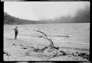 An unidentified man standing on the shore of a lake [Lake McKellar?], Greenstone Valley, Queenstown-Lakes District