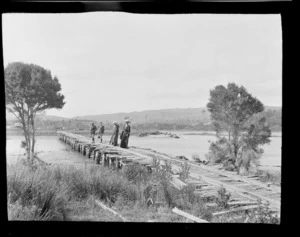 Group of two women and two young men, all unidentified, standing on a wooden railway bridge, Hamner Springs, Hurunui district, Canterbury region