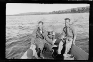 Two unidentified men riding in a small boat with an outboard motor, [Catlins district, Otago region?]