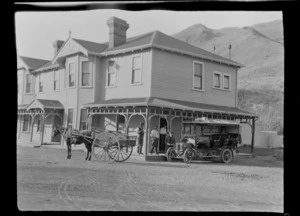 People on veranda of Ferry Bridge Hotel, Hanmer Springs, with Lydia Williams in the back of passenger vehicle and horse and cart in front, Canterbury Region